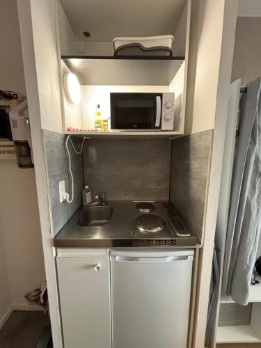 une petite cuisine avec un évier et un micro-ondes dans l'établissement Appartement Toulouse Crampel, à Toulouse