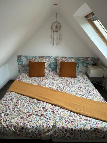 - une chambre avec un grand lit et une couverture fleurie dans l'établissement L'Echappée Verte - Guînes, maison 2 chambres à 25min du Site des 2 Caps, à Guînes