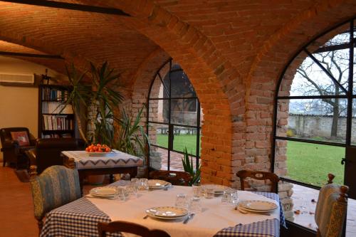 ein Esszimmer mit Tischen, Stühlen und Fenstern in der Unterkunft Agriturismo La Pieve in Dogliani