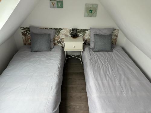 two beds in a small room with a table at L'Echappée Verte - Guînes, maison 2 chambres à 25min du Site des 2 Caps in Guînes