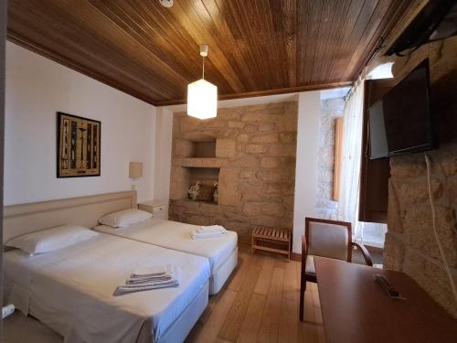 a hotel room with two beds and a television at Casa d Toninha - Casas de Campo - Turismo Espaço Rural - AL in Sernancelhe