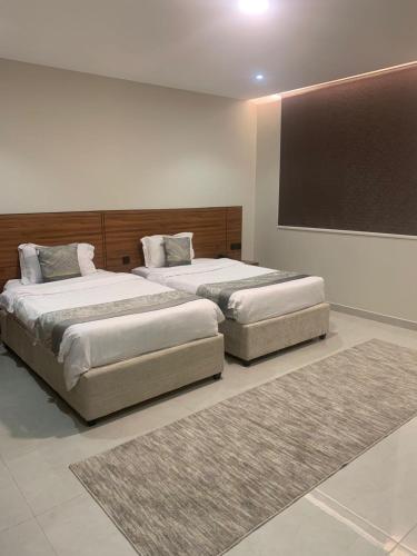 two beds in a room with two rugs at شقق ستار القمة للشقق المخدومة in Al Hofuf