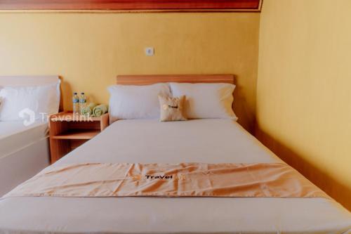 a bedroom with a white bed with white pillows at Vianda Cabin By Travelink in Kejajar