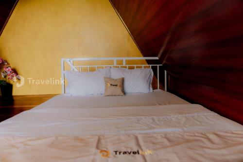 a bed with white sheets and pillows in a room at Vianda Cabin By Travelink in Kejajar