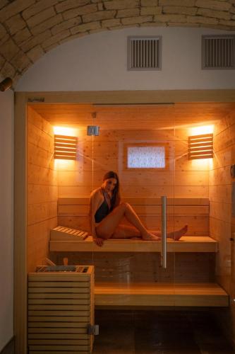 a woman sitting on a bed in a sauna at VILLA MADRE Suites e Private Spa in Grottaferrata