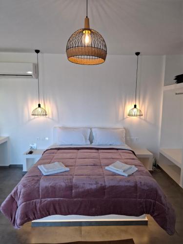a bedroom with a large bed and two lights at sea melody tinos 2 in Agios Sostis