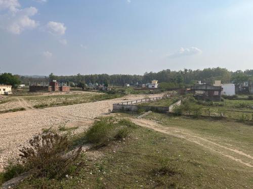 an empty field with a gravel road and houses at Sukoon Guaranteed in Jhājra
