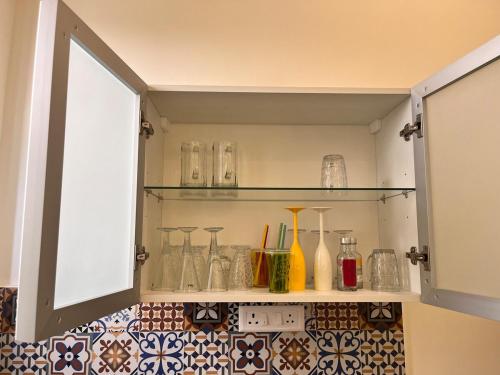 a cabinet filled with glass vases on a tiled floor at Sukoon Guaranteed in Jhājra