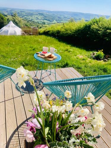 a table with two cups of coffee and flowers at Luxury Stargazing Glamping - Seren Aur with Hot Tub in Llanidloes