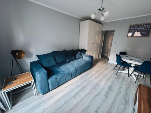 a living room with a blue couch and a table at Apartament Keja Olecko in Olecko