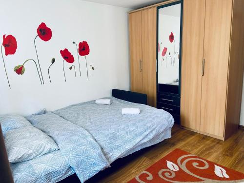 a bedroom with a bed with red poppies on the wall at Closca Apartment 1 Max in Floreşti