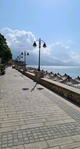 a sidewalk next to the ocean with street lights at Kelly's Rooms in Polisi i Vogël