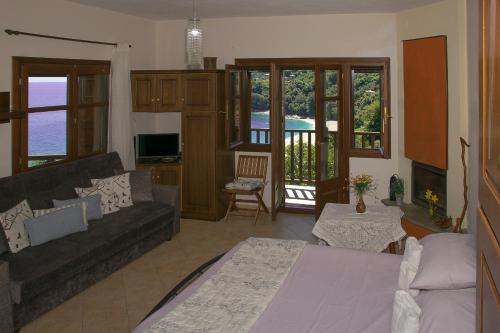 a living room with a couch and a tv at The Bird's Sea View in Agios Ioannis Pelio
