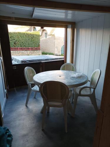 une table et des chaises dans une pièce avec une fenêtre dans l'établissement Maison 400ml a pied de la plage, à Erdeven