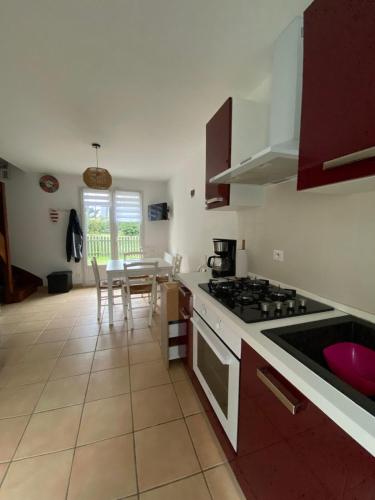 une cuisine avec une cuisinière et une table avec des chaises dans l'établissement Maison à 100m de la mer, à Piriac-sur-Mer