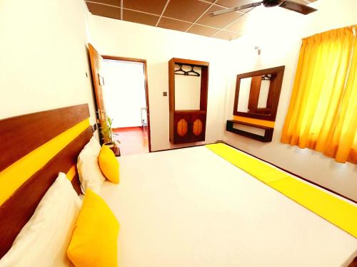 a bedroom with a large bed with yellow pillows at Coco Garden Villas 3 in Hikkaduwa
