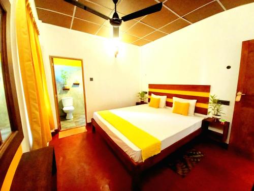 a bedroom with a large bed with yellow and white sheets at Coco Garden Villas 3 in Hikkaduwa