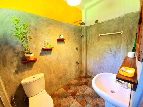 a bathroom with a white toilet and a sink at Coco Garden Villas 3 in Hikkaduwa