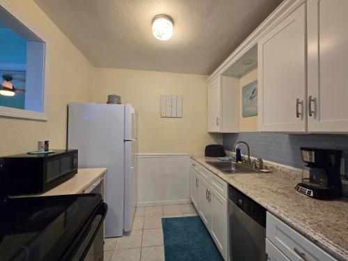 a kitchen with a white refrigerator and a sink at Oceanfront Sea Scape Motel in Melbourne