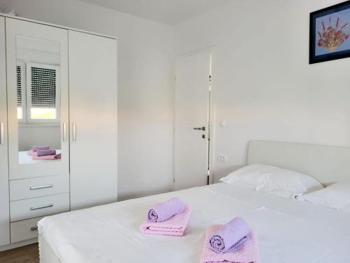 a white bedroom with pink towels on a bed at Jopy in Kaštela