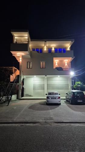 two cars parked in front of a house at night at White Luxury Villa Apartments &Hot Tab in Durrës