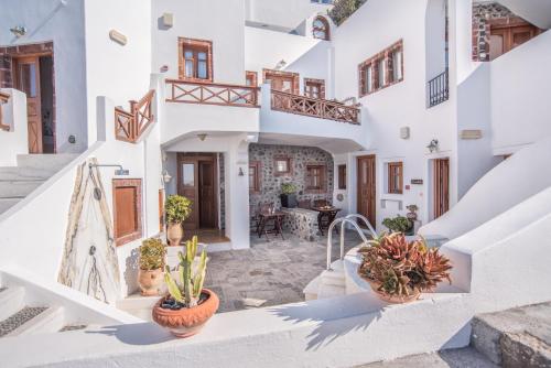 a house with white walls and stairs with potted plants at Smaro Studios in Firostefani