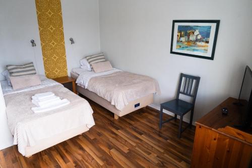 a room with two beds and a desk and a chair at Hotel Homeland in Tampere