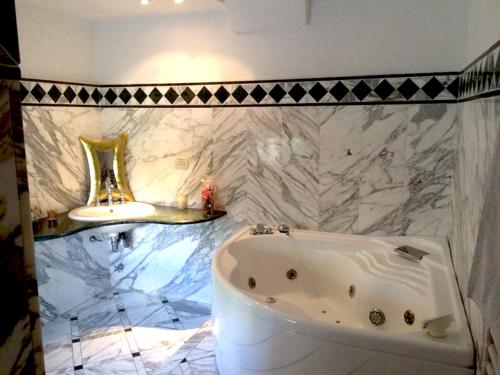 a bathroom with a white tub and a marble wall at Casa Bellavista in Sorrento
