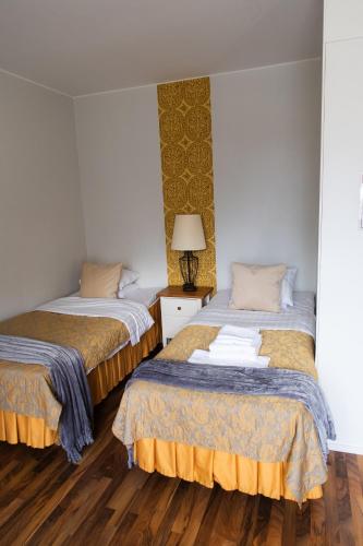 two beds in a small room with wooden floors at Hotel Homeland in Tampere