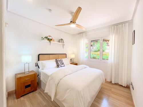 a white bedroom with a bed and a ceiling fan at Apartamento en Resort de lujo Isla del Fraile in Águilas