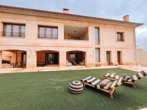 a house with a lawn with two chairs and a building at Casa Rural en Zamora Casa Bamba in Villalobos