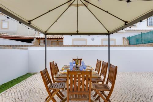 a wooden table with chairs and a large umbrella at Spacious Villa - Walk to Beach & City Center in Lagos