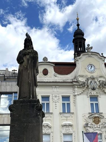 a statue in front of a building with a clock tower at Pension Kotva in Beroun