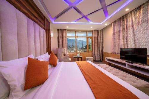 a bedroom with a large bed and a television at Hill River Resort By West Western in Manāli
