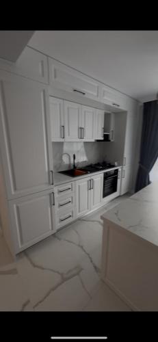 a white kitchen with white cabinets and a stove at Adu Luxuri apartament in Rădăuţi