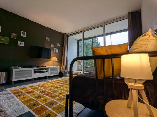 - une chambre avec un lit doté d'une lampe et d'une télévision dans l'établissement Refuge AuRoiSud, à La Bresse