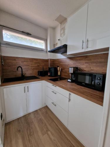 une cuisine avec des armoires blanches, un évier et un micro-ondes dans l'établissement Studio centre 100 m plage et port avec parking, à Saint Cyprien Plage