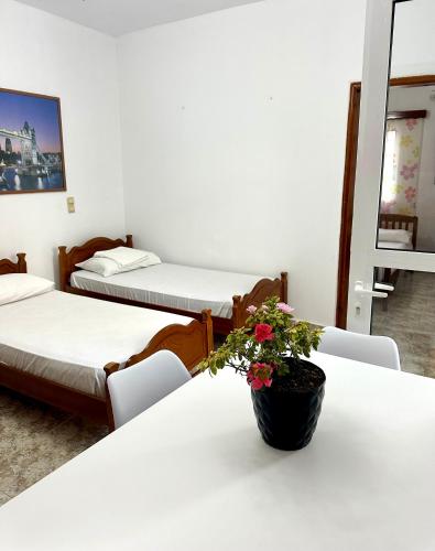 a room with three beds and a vase with flowers on a table at Chris apartament 2 in Polisi i Vogël