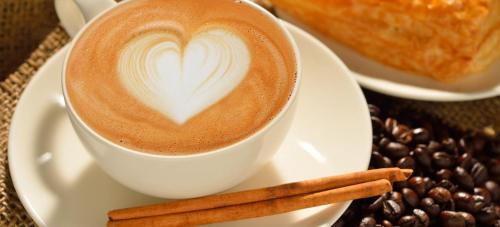 a cup of coffee on a plate with coffee beans at Boutique Hotel Tamarin in Rosh Pinna