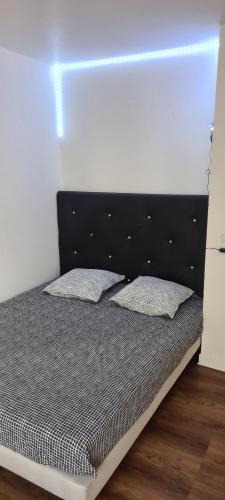 - un lit avec une tête de lit noire et 2 oreillers dans l'établissement Le prestige, à La Celle-sous-Gouzon