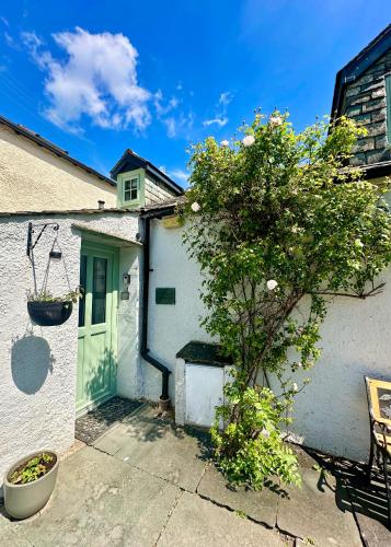 a white house with a green door and a tree at Cottage On The Brook in Braithwaite
