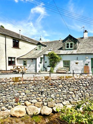 a stone wall in front of a building at Cottage On The Brook in Braithwaite