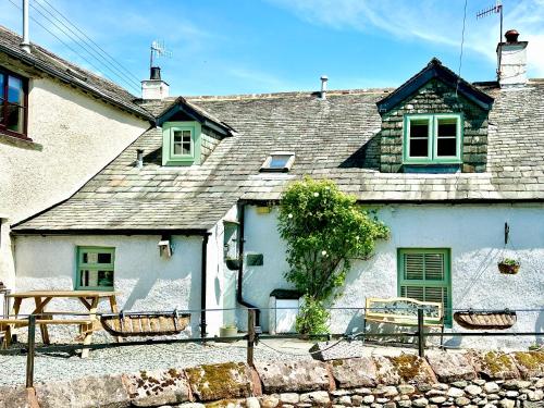 a white house with a bench in front of it at Cottage On The Brook in Braithwaite