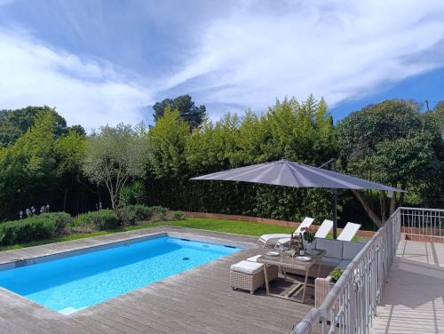 une piscine avec un parasol, une table et des chaises dans l'établissement Villa près de la mer, à Vallauris
