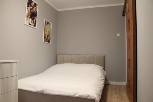 a small bedroom with a bed with white sheets at zloty zakątek in Chojna