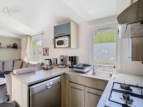 une cuisine avec un évier et une cuisinière four supérieur dans l'établissement Mobil-home JA 68 à Vias - La Carabasse - Camping Siblu avec Piscine, à Vias