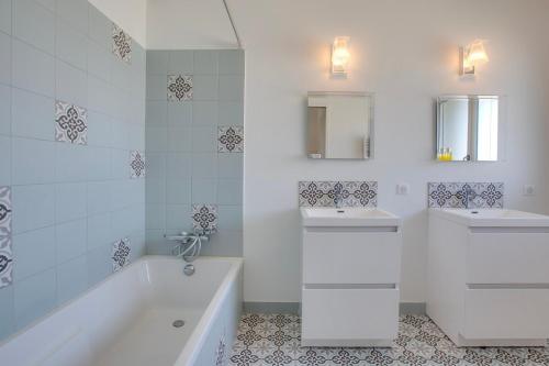 La salle de bains blanche est pourvue de 2 lavabos, d'une baignoire et d'une baignoire. dans l'établissement Villa Landa, à Angresse