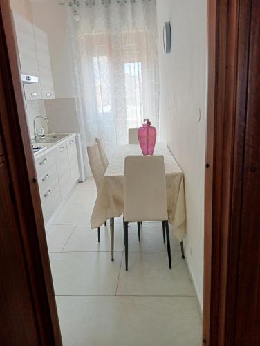 a dining room with a table and a pink vase on it at Casa Karmel in Campofelice di Roccella
