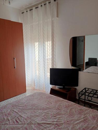 a bedroom with a bed and a flat screen tv at Casa Karmel in Campofelice di Roccella