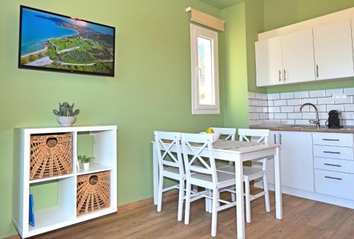 a kitchen with a white table and chairs and a tv on the wall at 7 Grapes in Eleftheres